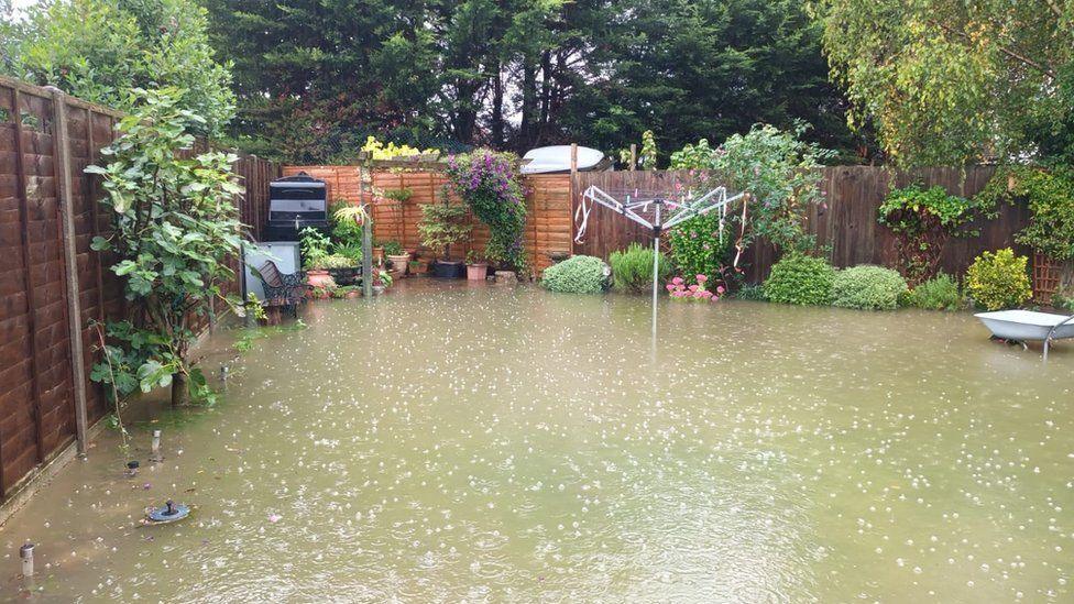 Wooden fenced garden under floodwater with washing line and plants around its edge