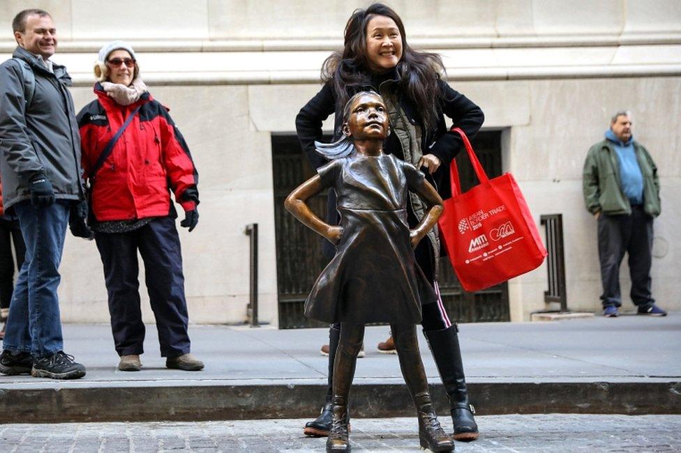 A woman poses with the Fearless Girl statue at its new location outside the New York Stock Exchange in New York on 10 December 2018