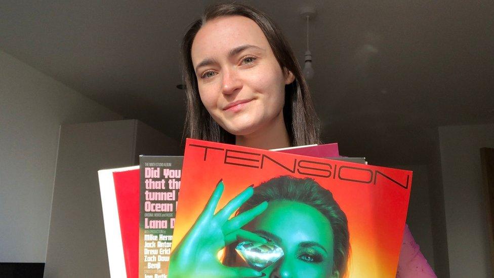 Bethan Currie holding three vinyl records and smiling behind them.