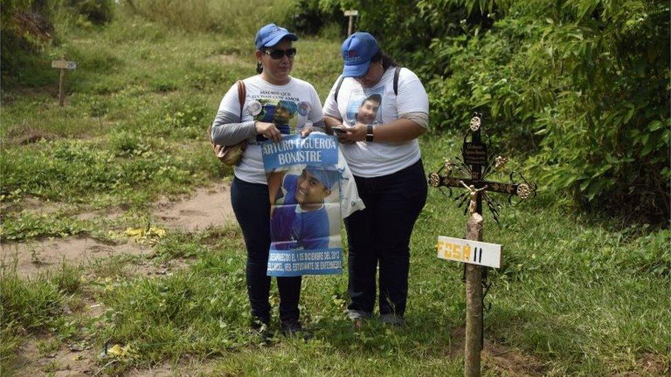 A woman and her daughter stand by the grave of their son and brother