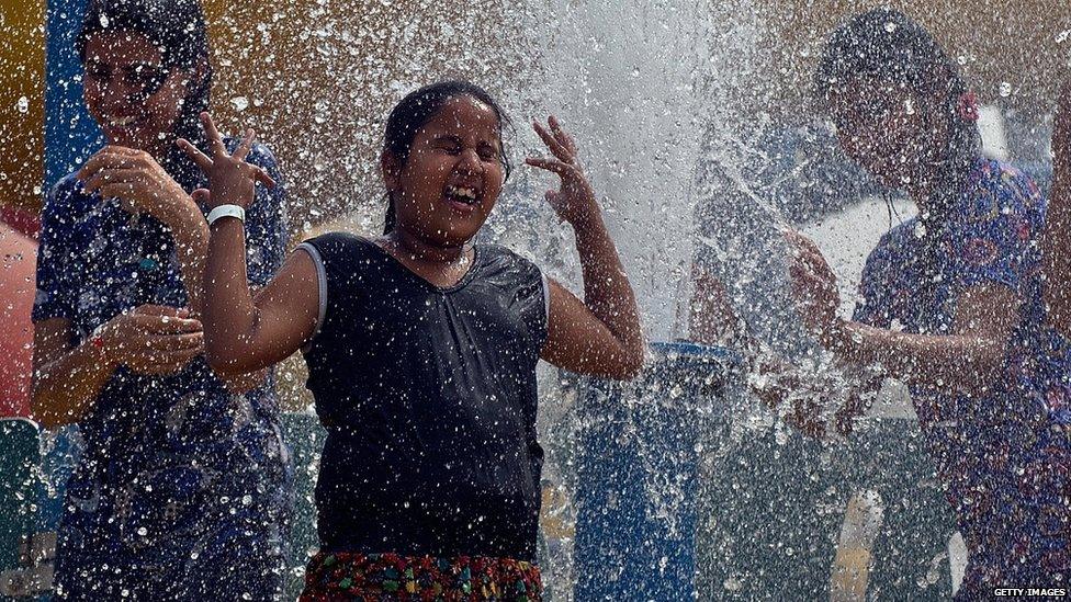 An Indian child plays in a fountain at the World of Wonder water park in Noida, some 20 kms east of New Delhi 30 May 2014