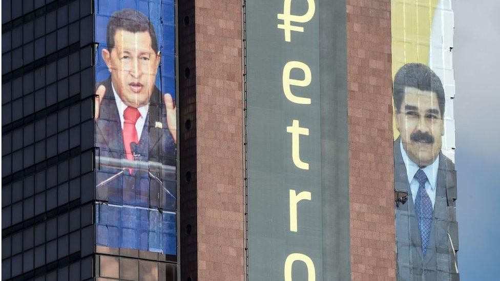 The logo of the 'Petro' is displayed next to images of former Venezuelan president Hugo Chavez and current President Nicolas Maduro on a building in Caracas