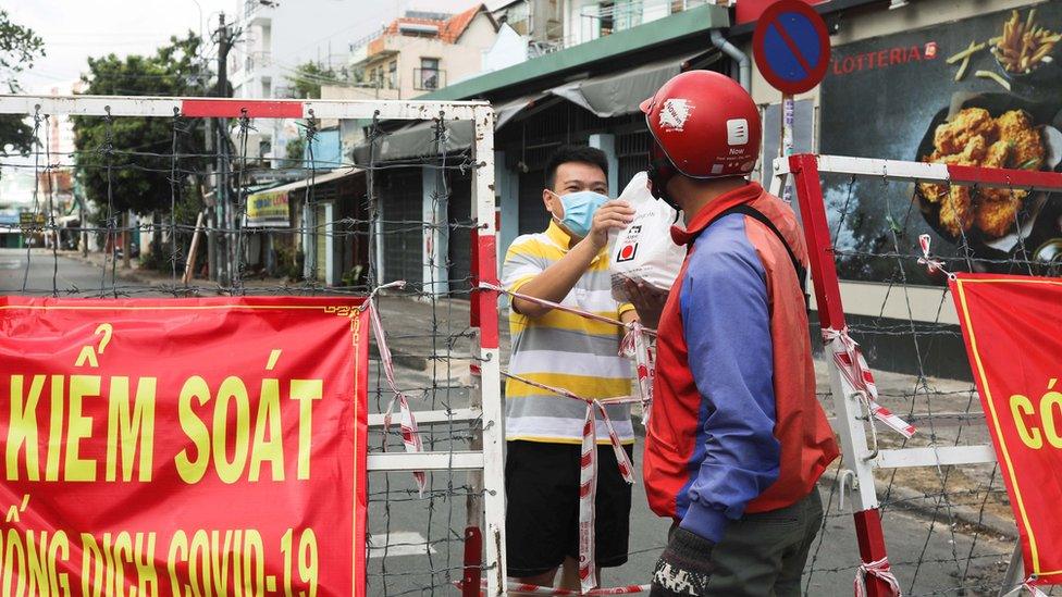 A man is handed food in an area of Ho Chi Minh under lockdown