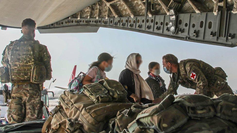 UK troops help Afghan nationals board an RAF plane in Kabul