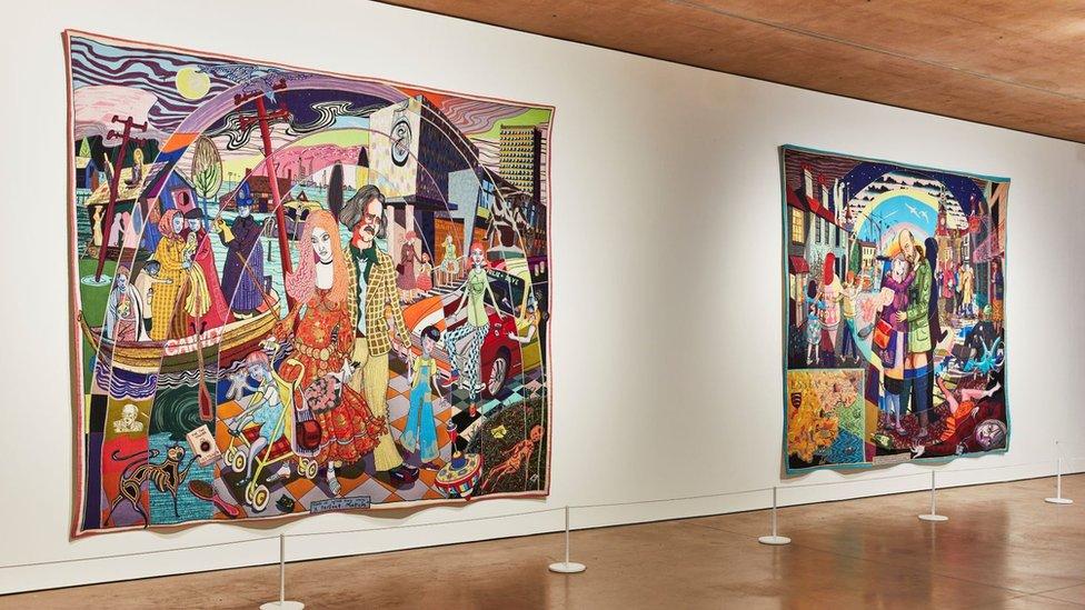 Two vivid and large tapestries side by side on an art gallery wall