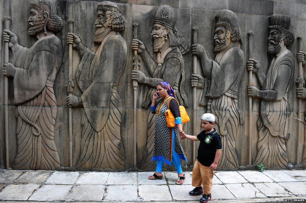 A Parsi devotee and child walk past a sculpture after offering prayers at a fire temple in Mumbai