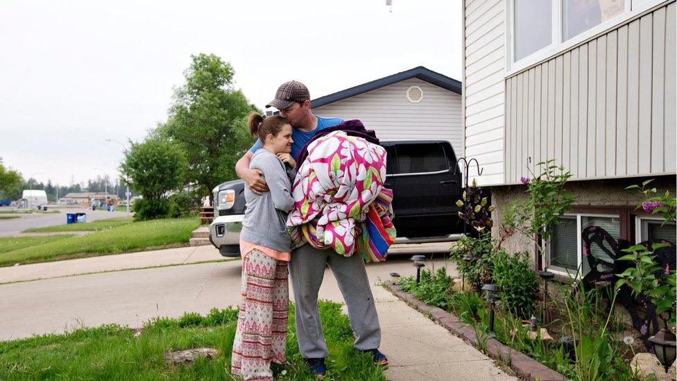 Mike Maloney and his wife Tessa Maloney, hug as they unpack to re-enter their home after being evacuated due to wildfires, in Fort McMurray, Alberta, on Wednesday 1 June 2016.