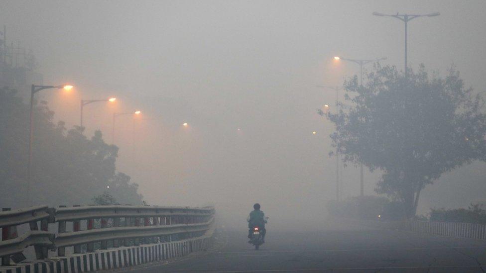 A man rides a scooter on a road enveloped by smoke and smog, on the morning following Diwali festival in New Delhi, India, Monday, Oct. 31, 2016