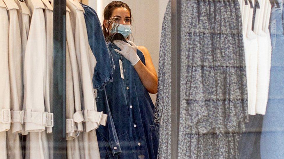 A worker changes clothes rails in a store