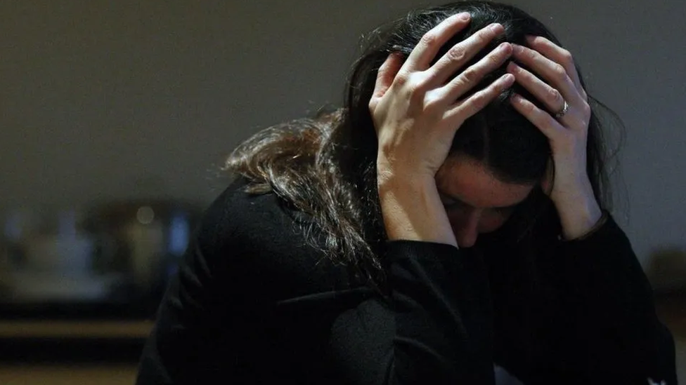 Image of woman with her head in her hands, showing distress