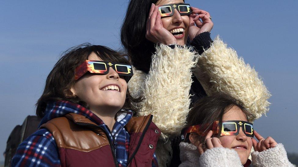 People watching eclipse with protective glasses