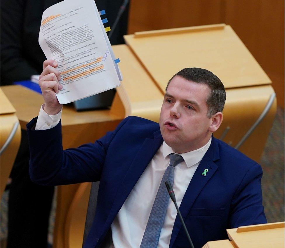 Douglas Ross holds up papers