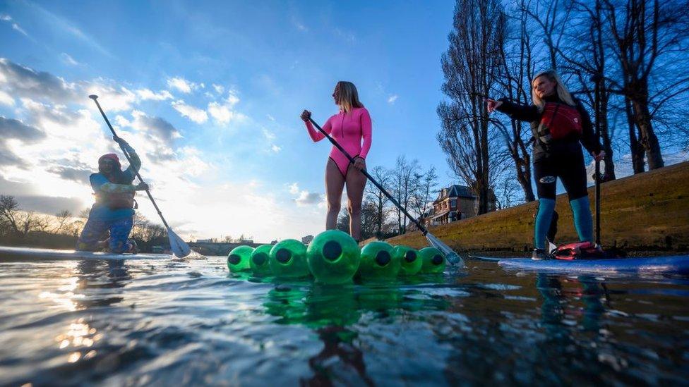 Climate change protesters surfing on the River Thames in March to raises awareness on the need to combat climate change