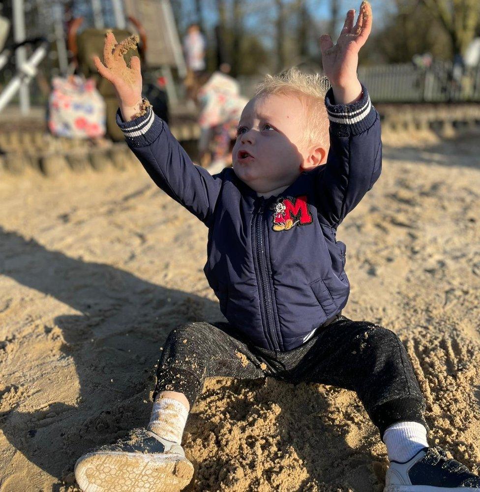 Harry Jackson playing in the sand in a playground