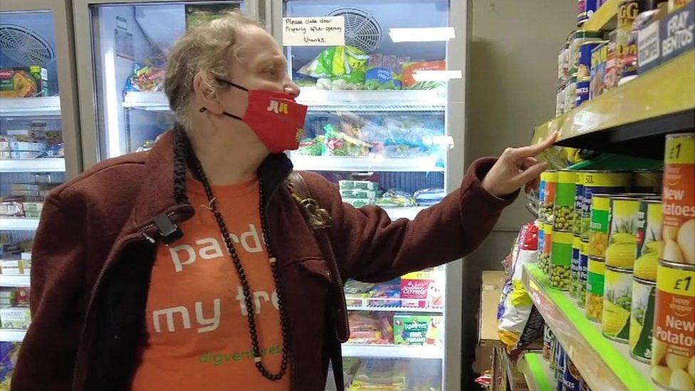 Tracey Rheged-Armer checking price of tins in a supermarket