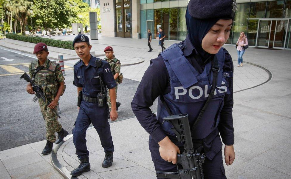 Malaysian military and police personnel patrol an outside shopping mall in Kuala Lumpur