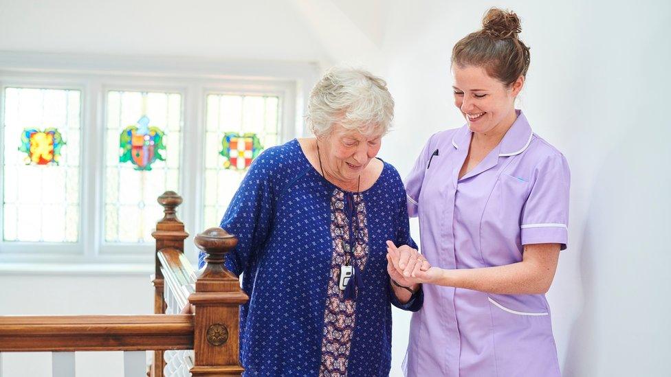 Nurse helping an older woman up the stairs