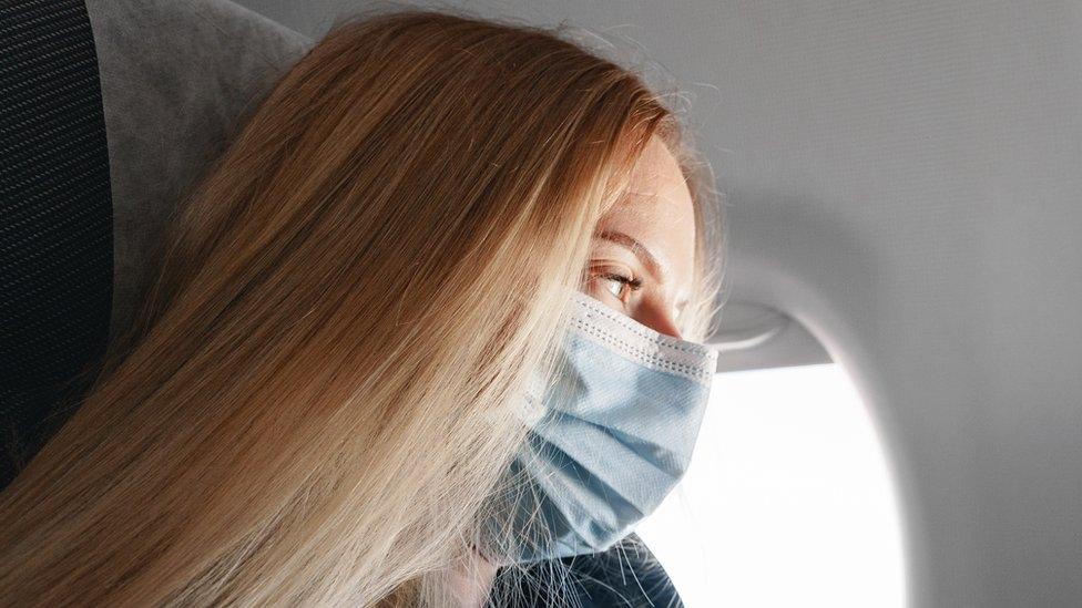 A woman wearing a medical mask on board a plane