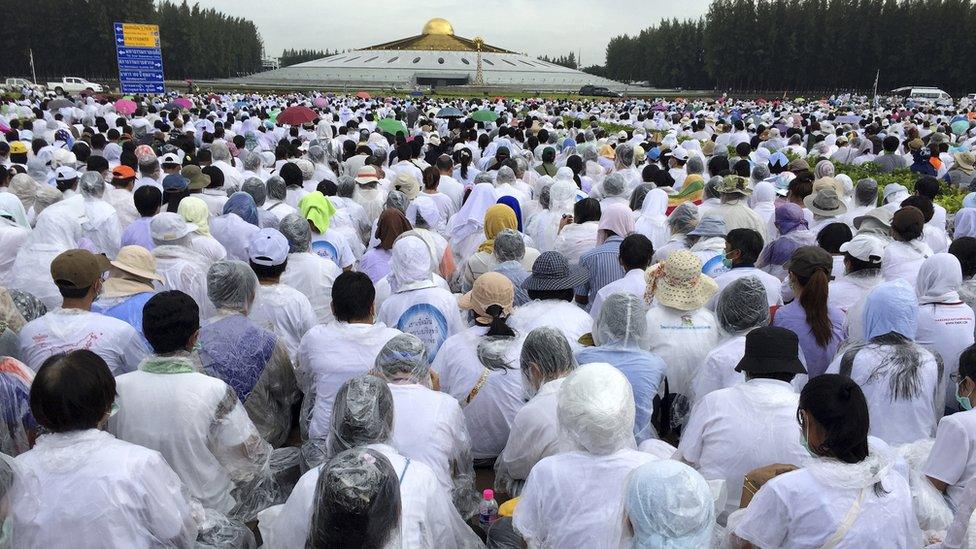 Buddhist devotees sit outside the Wat Phra Dhammakaya temple in Pathum Thani province, north of Bangkok, Thailand, Thursday, June 16, 2016.