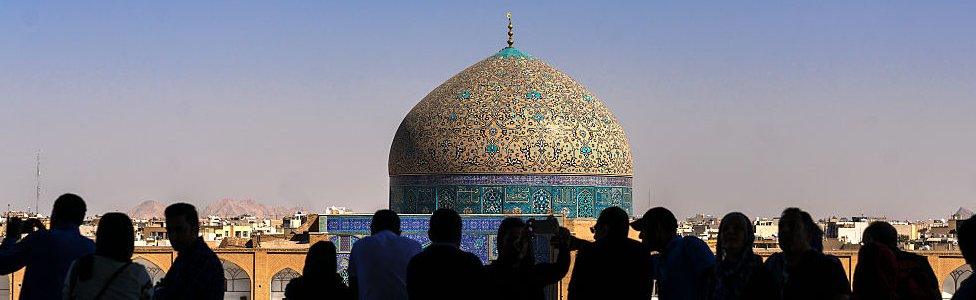 Silhouettes of tourists looking at Sheikh Lutfollah Mosque standing on the eastern side of Naqsh-e Jahan Square