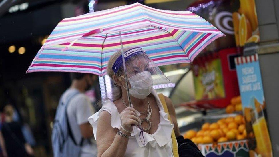 A woman shields from rain on Oxford Street in London