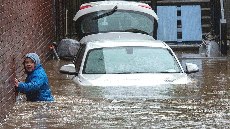 A boy wades towards a flooded alleyway in Pontypridd on Sunday