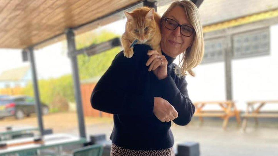 Ginger tom Peanut sitting on the shoulder of Diane Maher, landlady of the George Hotel, in Chatteris