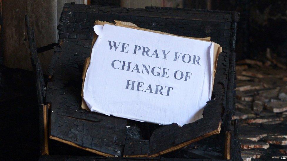 Sign in St Sebastian's Church reading "We pray for change of heart"