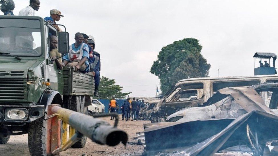 Security personnel sitting on a truck watch burned vehicles at the front gate of the Makala prison after it was attacked by supporters of jailed Christian sect leader Ne Muanda Nsemi in Kinshasa, Democratic Republic of the Congo May 17, 201