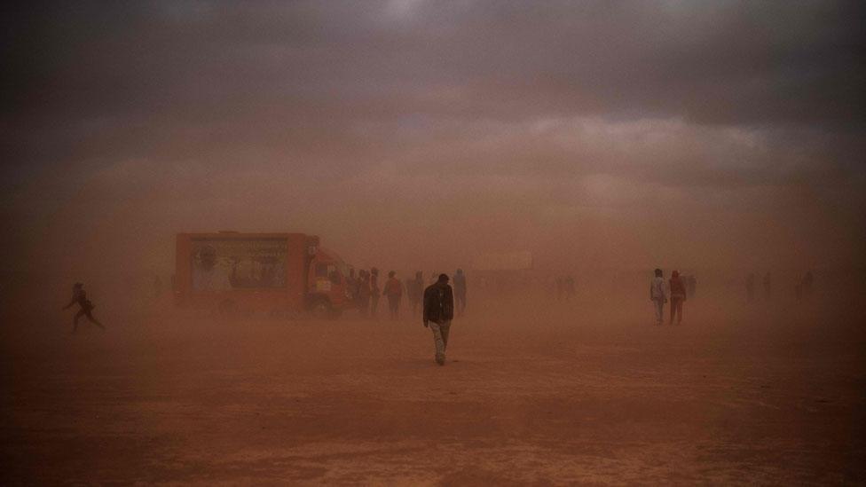 People walking to the mass in the dust