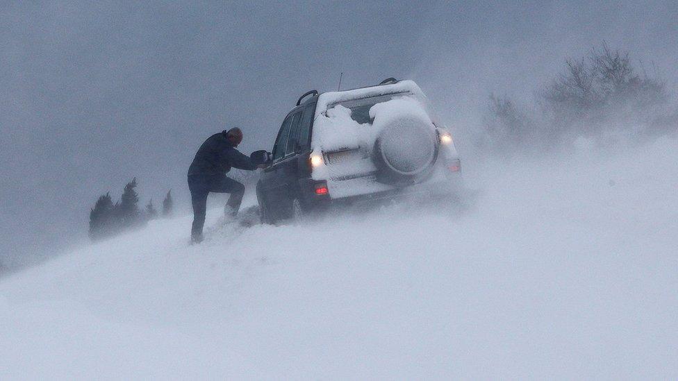 A man tries to dig his car out of snow