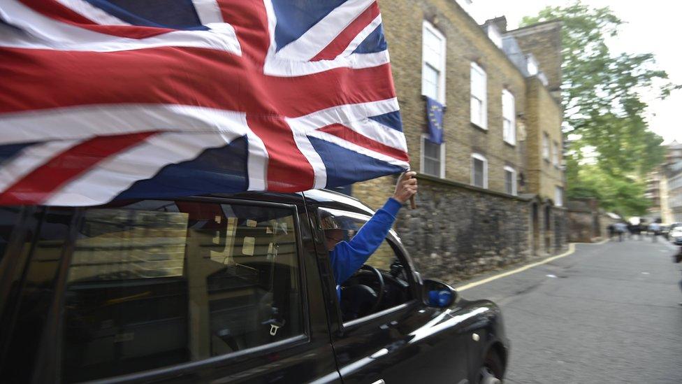 A taxi driver holds a Union flag, as he celebrates following the result of the EU referendum