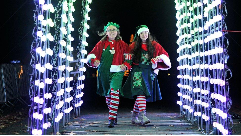 Two women dressed as elves walking under an illuminated walkway