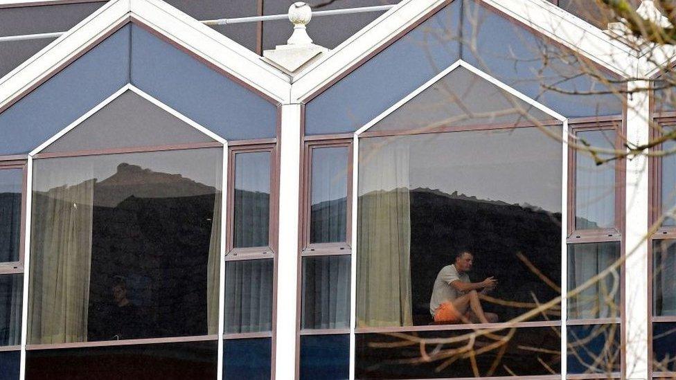 A man sits at a window of the Radisson Blu hotel at Heathrow Airport in west London