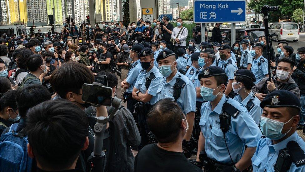 Police officers stand guard as pro-democracy supporters gather outside the West Kowloon court in Hong Kong, 1 March 2021