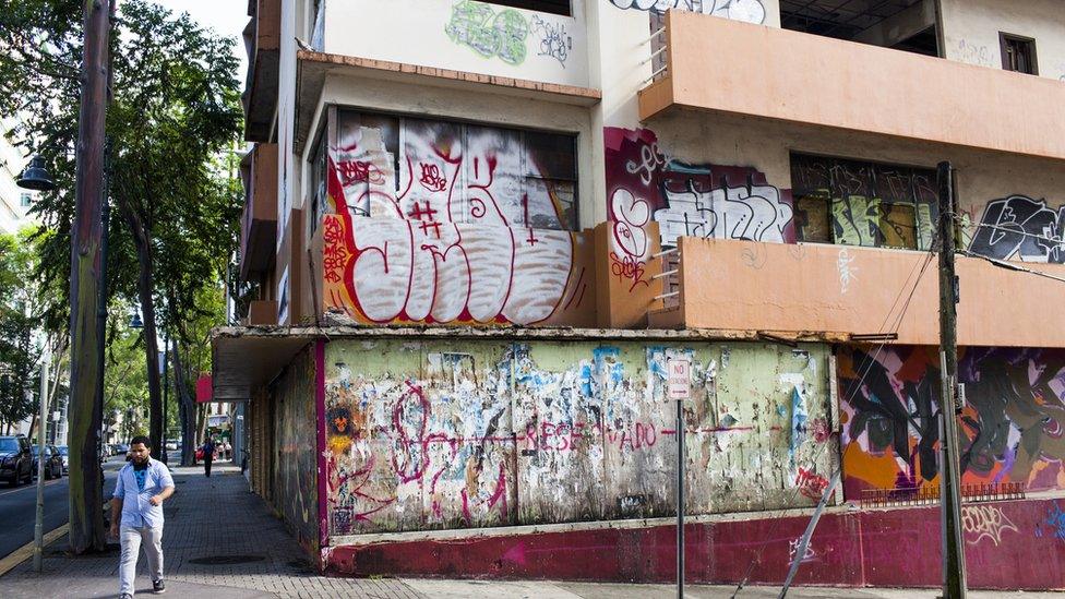 A man walks past a vacant building on 12 November 2013 in the Santurce neighbourhood of San Juan, Puerto Rico.