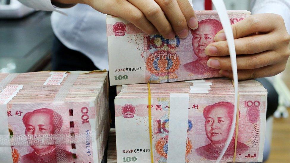 A woman holding bundles of yuan notes