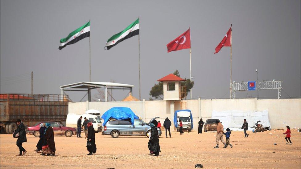 Syrian walk near the Bab al-Salam border crossing with Turkey, in Syria, Saturday, Feb. 6, 2016