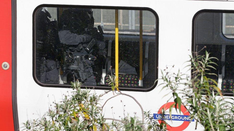 Armed police walk through an underground train