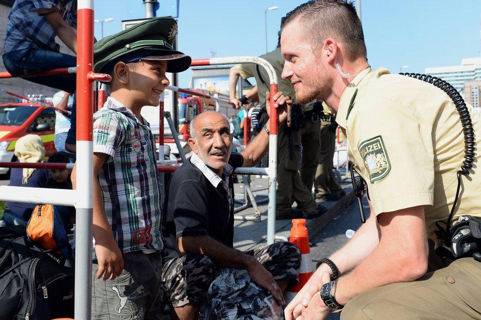 Refugee boy wearing German policeman's hat in Munich, 1 Sep 15