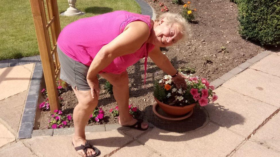 Lynn Wright in her garden next to a pot of flowers