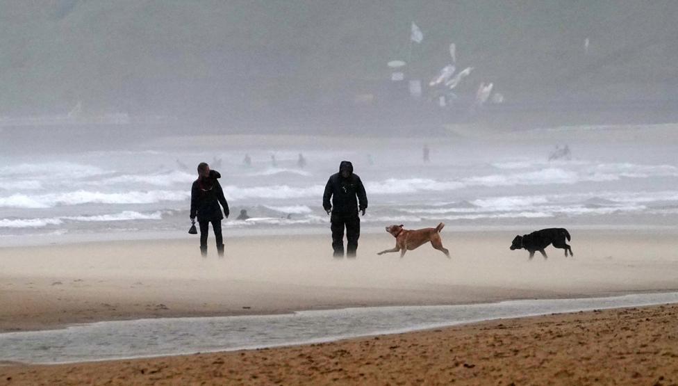 Walkers on a windy Tynemouth beach