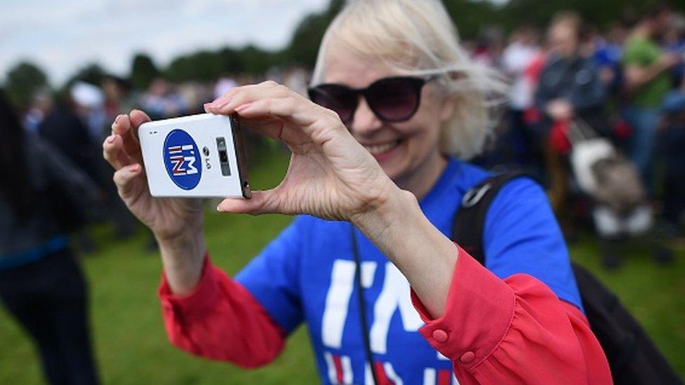 Young person holding phone with tag saying "I'm In"