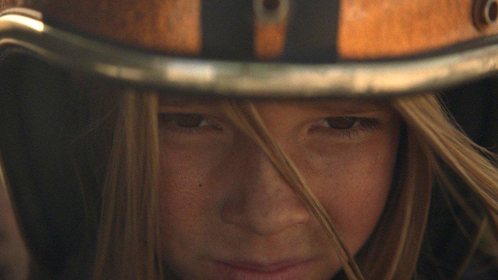 The young girl crouches to start the race.