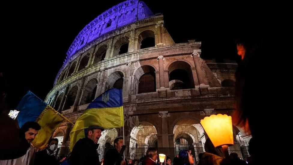 A torchlight procession took place outside the famous Colosseum in Rome, Italy as the monument was lit up in blue and yellow.