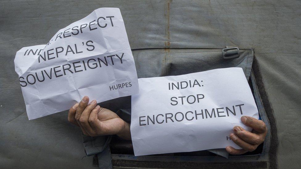 Activists affiliated with Human Rights and Peace Society Nepal hold signs in the back of a police vehicle during an anti-Indian-government protest at the Indian Embassy in Kathmandu, Nepal, 12 May 2020.