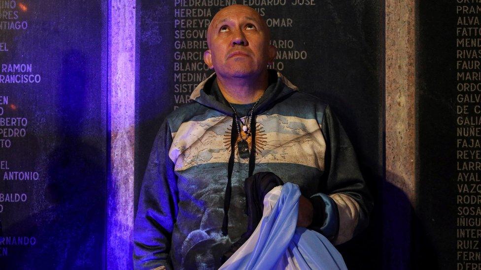 An Argentinian holds his country"s flag in front of a memorial dedicated to those who died in the 1982 war