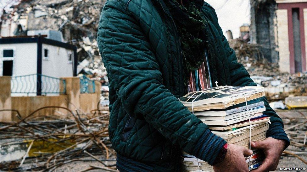 An Iraqi students carries books away from the ruins of the university