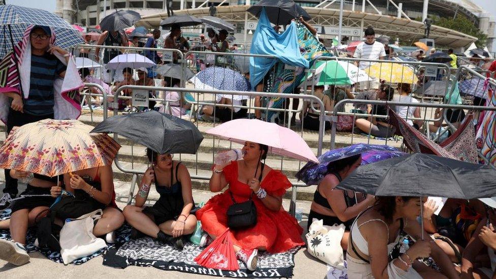 Fans in Rio shelter from the heat ahead of Swift's now postponed Saturday concert