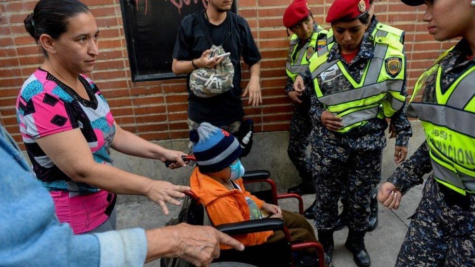 A woman pushing a wheelchair with a child at a health workers protest outside the "Dr J M de los Rios" Children's Hospital in Caracas 16 August 2018.